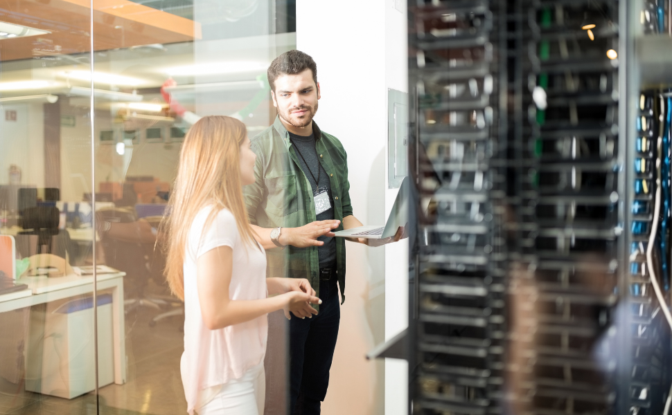 best web hosting - two business people standing in server room with laptop and discussing