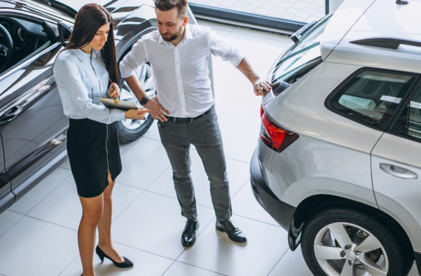 Salesman and woman looking for a car in a car showroom
