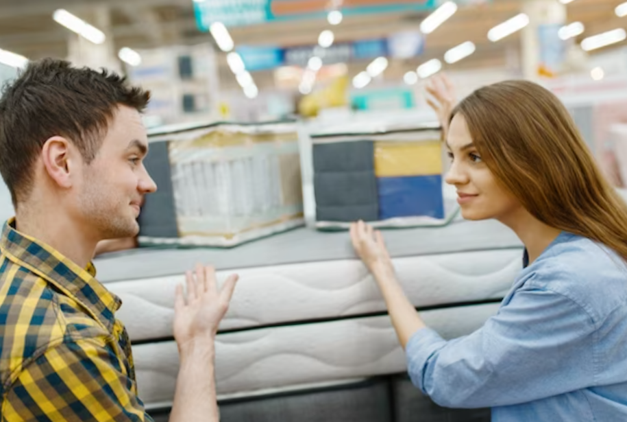 love couple choosing mattress for the bed in furniture store showroom. man and woman looking samples for bedroom in shop, husband and wife buys goods for modern home interior