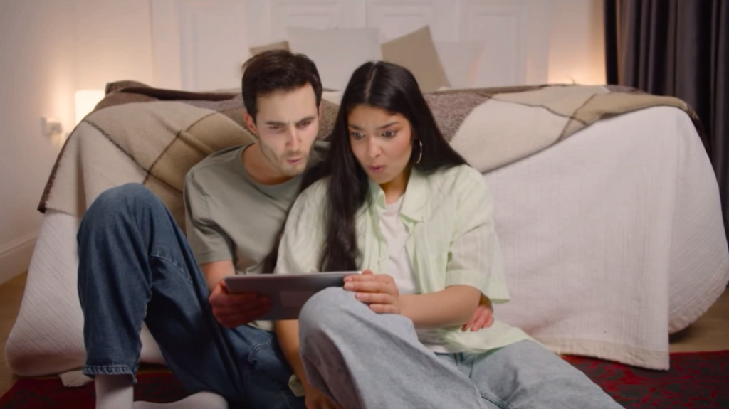 Couple watching unexpected movie scene on tablet while sitting on the floor at home 1